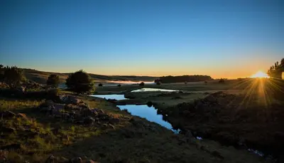 a sunset over a river in a field at LINGER LONGER COUNTRY RETREAT, Dullstroom in Dullstroom