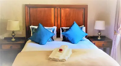a bed with blue pillows and a towel on it at LINGER LONGER COUNTRY RETREAT, Dullstroom in Dullstroom
