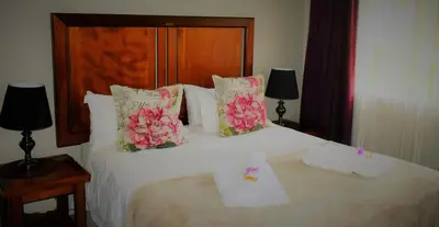 a bedroom with a white bed with flowers on it at LINGER LONGER COUNTRY RETREAT, Dullstroom in Dullstroom