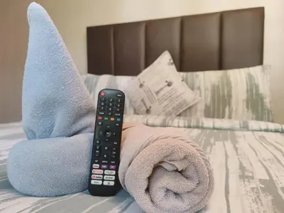 a remote control sitting on a bed with a towel at Golf B&B in Nelspruit