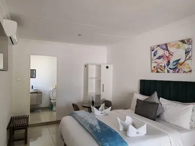 a bedroom with a large white bed and a table at Golf B&B in Nelspruit