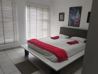 a bed with a red blanket on it in a bedroom at Elephant hide away in Witbank
