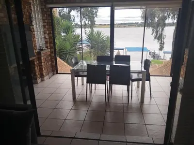 a dining room table with chairs and a view of the water at Elephant hide away in Witbank