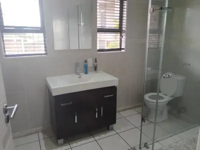 a bathroom with a sink and a shower and a toilet at Elephant hide away in Witbank