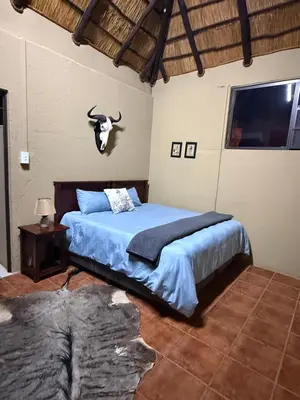 a bedroom with a bed with a bull skull on the wall at Kaalkraal Safari Lodge