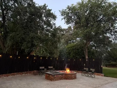a fire pit in a backyard with chairs and a fence at Kaalkraal Safari Lodge