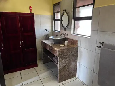 a bathroom with a sink and a mirror at Kaalkraal Safari Lodge
