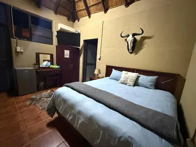 a bedroom with a bed with a bull skull on the wall at Kaalkraal Safari Lodge