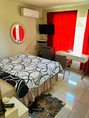a bedroom with a bed and a desk and red curtains at Kasi Retreat in Northam