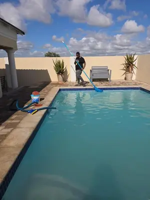 a man with a hose cleaning a swimming pool at Bigmor guesthouse Eldorado