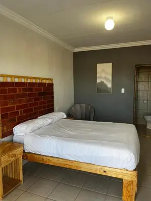 a bedroom with a large bed with a brick wall at Bigmor guesthouse Eldorado