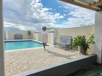 a woman is standing next to a swimming pool at Bigmor guesthouse Eldorado