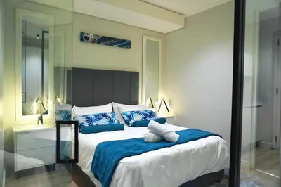 a bedroom with a large bed with blue pillows at Elipse Waterfall Luxe Executive Apartment in Midrand