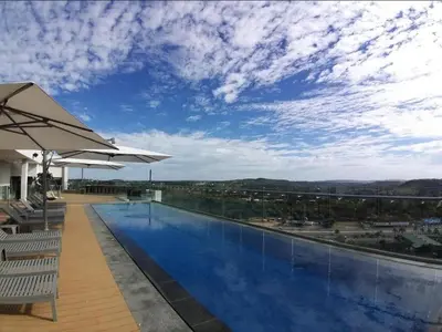 a swimming pool with chairs and an umbrella at Menlyn Pretoria 732 in Pretoria