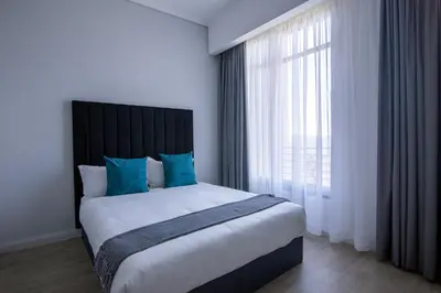 a bedroom with a large bed with blue pillows and a window at Menlyn Pretoria 732 in Pretoria