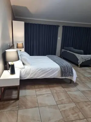 a bedroom with a bed and a table with a lamp at Sunset Retreat in Polokwane