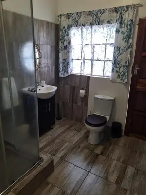 a bathroom with a toilet and a sink and a window at Sunset Retreat in Polokwane
