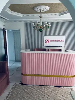 a lobby with a pink counter with chairs and a sign at Euphoria Escape in Midrand
