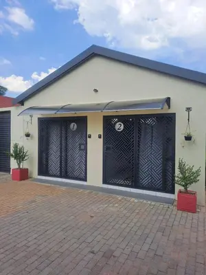 a white house with black gates on it at Close to O R Tambo Airport Alderlane 1 in Kempton Park