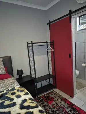 a bedroom with a red door and a bed and a bathroom at Close to O R Tambo Airport Alderlane 1 in Kempton Park