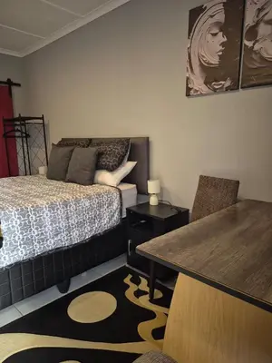 a bedroom with a bed and a table and chair at Close to O R Tambo Airport Alderlane 1 in Kempton Park