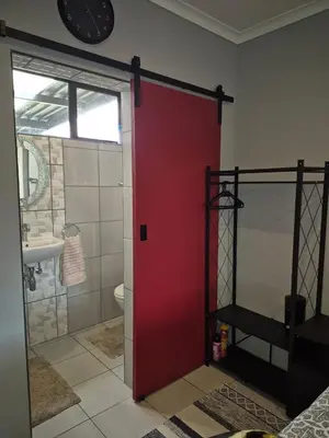 a red door in a bathroom with a toilet and a sink at Close to O R Tambo Airport Alderlane 1 in Kempton Park