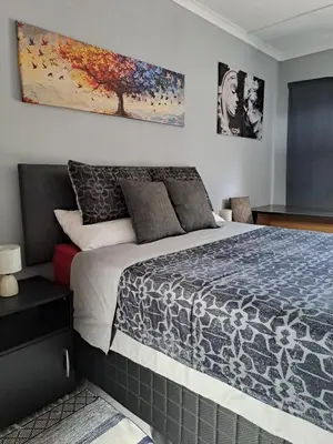 a bedroom with a bed and a painting on the wall at Close to O R Tambo Airport Alderlane 1 in Kempton Park