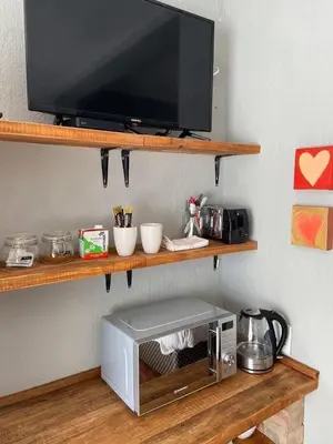 a tv on a shelf with a microwave on a table at Menatwork contractors accommodation in Nelspruit