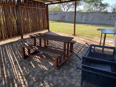 a picnic table and a grill on a patio at Menatwork contractors accommodation in Nelspruit