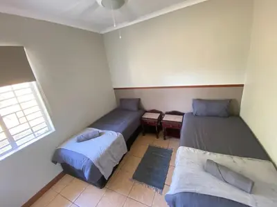 a small room with two beds and a window at Menatwork contractors accommodation in Nelspruit