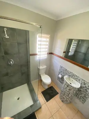 a bathroom with a glass shower and a toilet at Menatwork contractors accommodation in Nelspruit