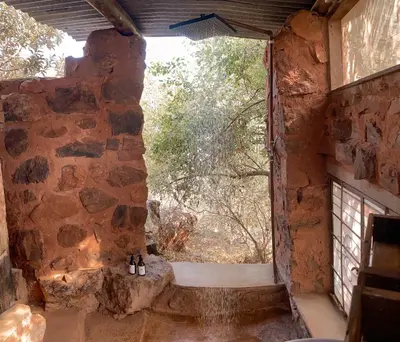 a window in a stone building with a view of a tree at Aloe Lodge in Thabazimbi