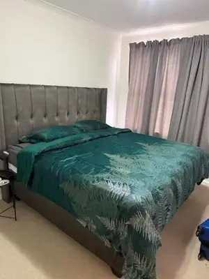 a bedroom with a bed with a green comforter and a window at The Oxford Haven