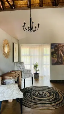 a living room with a chandelier and a desk at La Dolce Vita Lodge in Hoedspruit