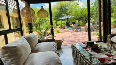 a living room with a couch and a large window at La Dolce Vita Lodge in Hoedspruit