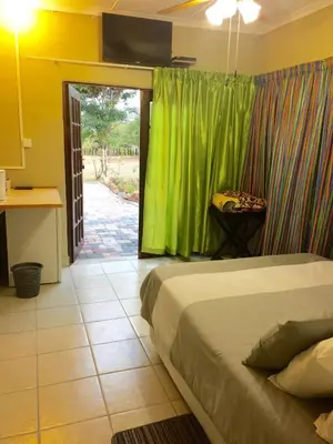 a bedroom with a bed and a green curtain at Klein Paradys Lodge - Polokwane in Polokwane
