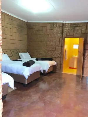 a bedroom with two beds and a cat laying on the bed at Klein Paradys Lodge - Polokwane in Polokwane