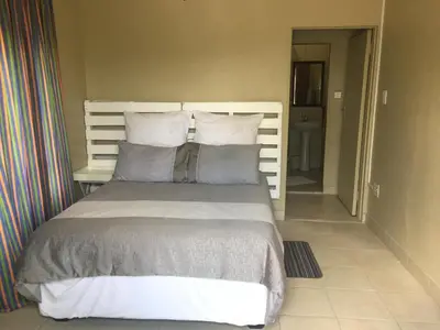a bedroom with a bed with pillows at Klein Paradys Lodge - Polokwane in Polokwane