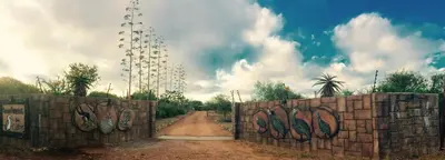 a gate with graffiti on it on a dirt road at Klein Paradys Lodge - Polokwane in Polokwane