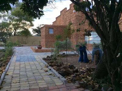two people standing in front of a brick building at Klein Paradys Lodge - Polokwane in Polokwane