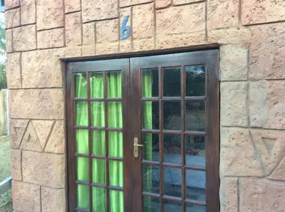 a door to a stone building with green curtains at Klein Paradys Lodge - Polokwane in Polokwane