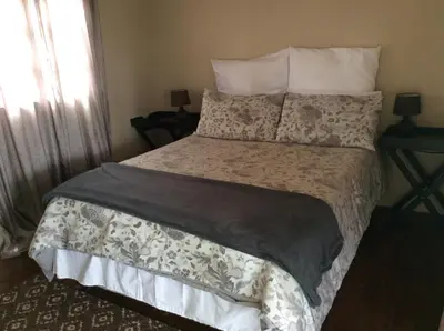 a bedroom with a large bed with a gray and white comforter at Klein Paradys Lodge - Polokwane in Polokwane