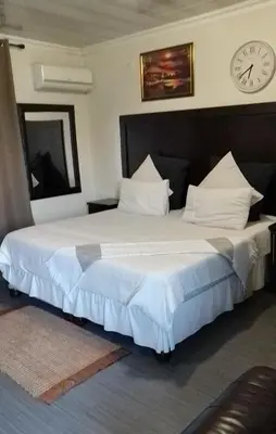a bedroom with two beds with a clock on the wall at Ermelo Executive Rooms in Ermelo