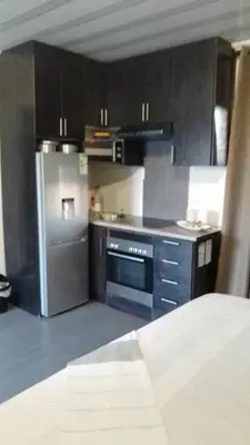 a kitchen with black cabinets and a stainless steel appliance at Ermelo Executive Rooms in Ermelo