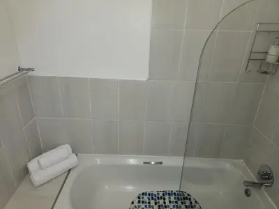 a bathroom with a tub with a glass shower door at Lovely one bedroom apartment in Midrand