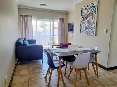 a living room with a dining room table and chairs at Lovely one bedroom apartment in Midrand