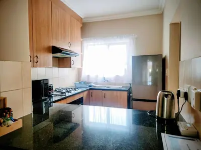 a kitchen with wooden cabinets and a black counter top at Lovely one bedroom apartment in Midrand