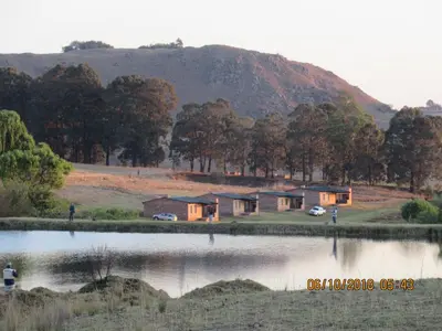 a row of houses next to a body of water at Elandskloof Trout Farm in Dullstroom