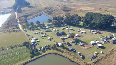an aerial view of a field with tents and a lake at Elandskloof Trout Farm in Dullstroom