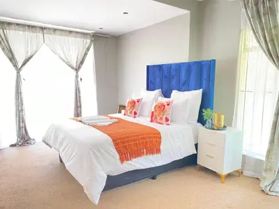 a bedroom with a bed with a blue headboard and pillows at Ranx Guest House in Pretoria